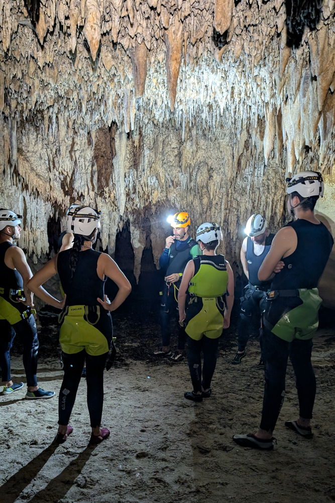 Gruppe mit Höhlenausrüstung unter beeindruckenden Tropfsteinformationen in der Cova des Coloms auf Mallorca