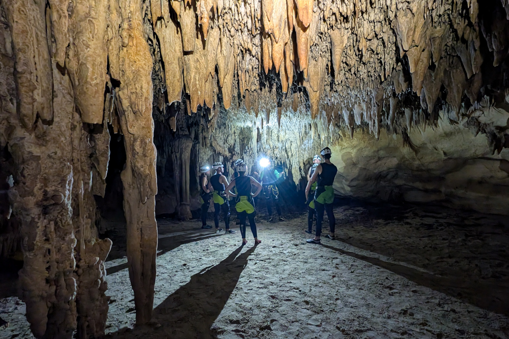 Gruppe mit Helmen erkundet die Tropfsteinformationen im Inneren der Cova des Coloms