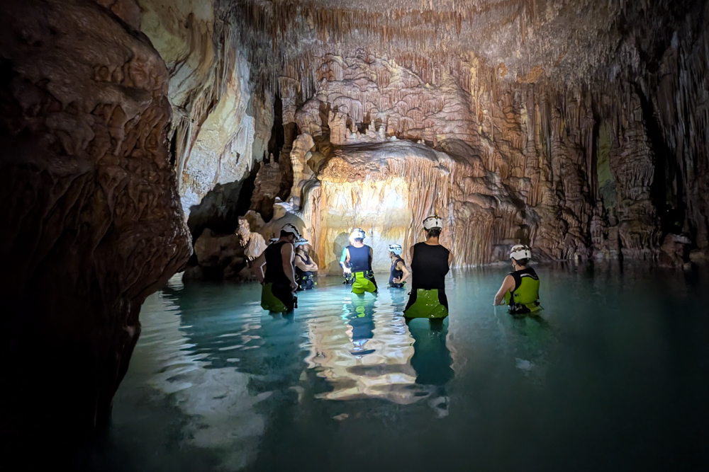 Gruppe mit Neoprenanzügen erkundet das Wasserinnere der Cova des Coloms auf Mallorca