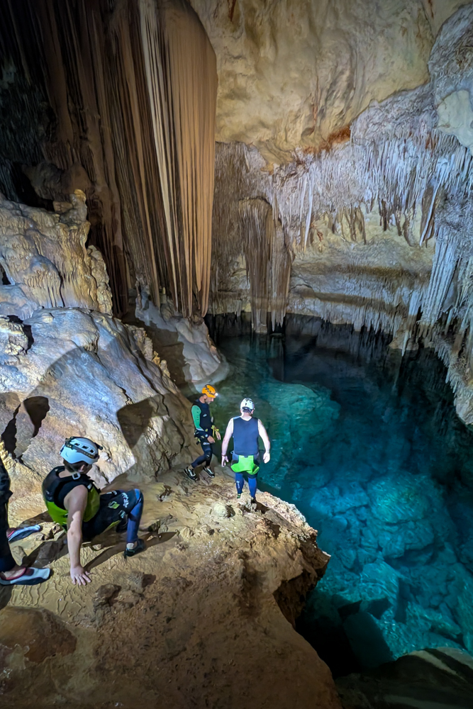 Blick auf das unterirdische Wasserbecken der Cova des Coloms mit Teilnehmern der Höhlentour und beeindruckenden Felsformationen