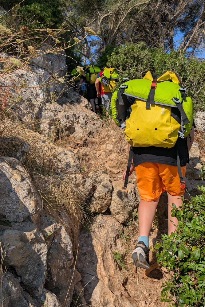 Gruppe auf dem Weg zur Cova des Coloms mit Neoprenausrüstung durch felsiges Gelände auf Mallorca